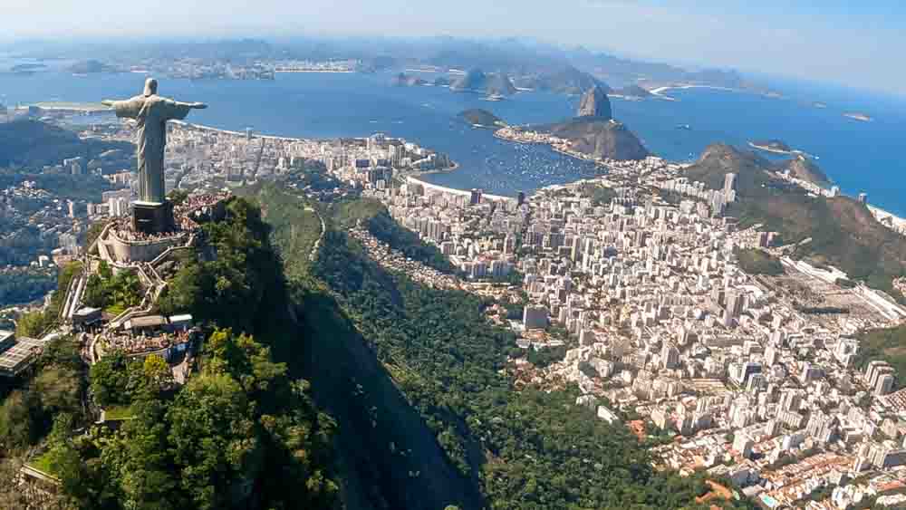 Foto do Cristo Redentor de frente para o Pão de Açúcar e Baia de Guanabara com Niterói ao fundo - Passeio de Helicóptero no Rio de Janeiro